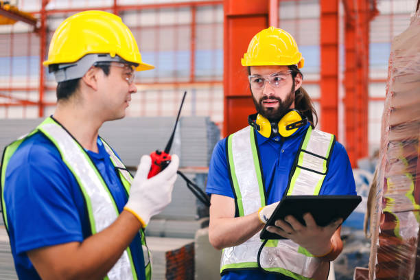 istock Young bearded caucasian worker holding digital tablet and talk to co-worker with walkie talkie about storing product. 2156204044