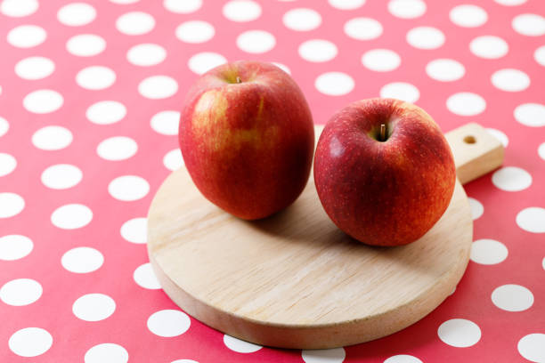 Ripe organic red apple on polka dot table background.