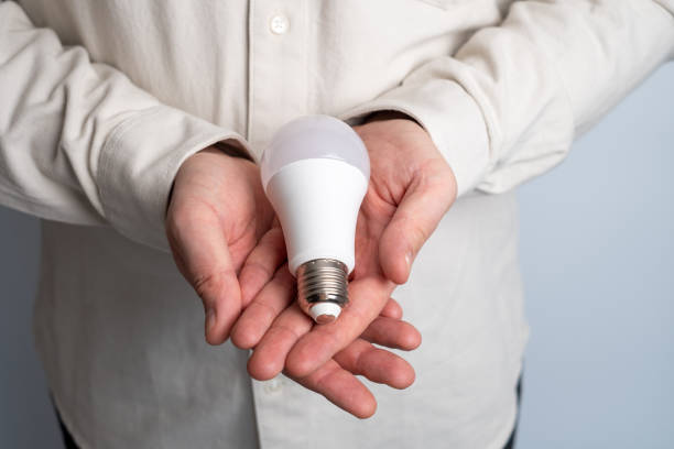 istock Man holds a light bulb and a clock in his hands. Concept of inspiration, creative idea, thinking and future technological innovation 2156207506