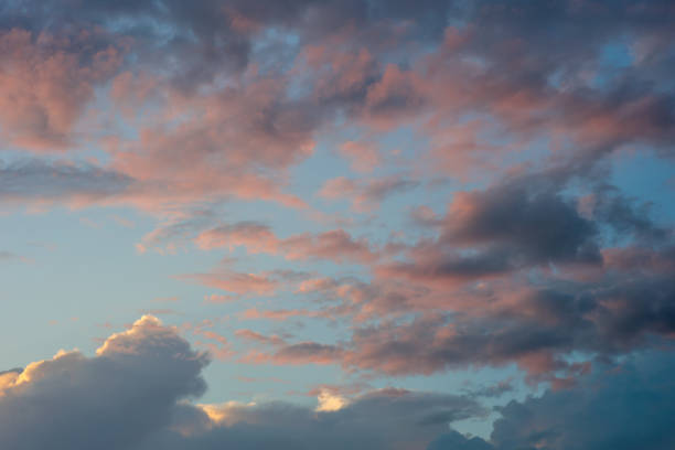 The sky is filled with clouds and the sun is setting. The sky is a mix of blue and pink, creating a beautiful and serene atmosphere