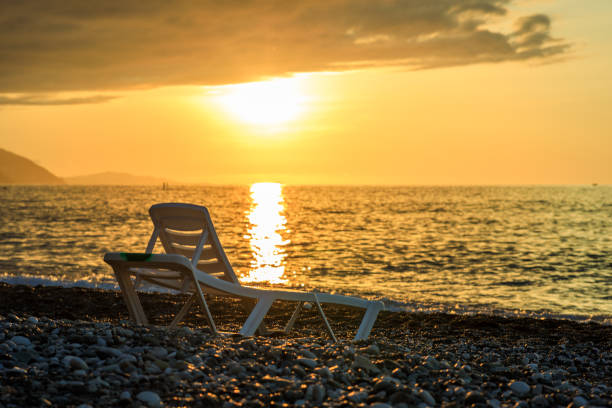 Broken plastic chair on a sandy beach in summer morning, selective focus
