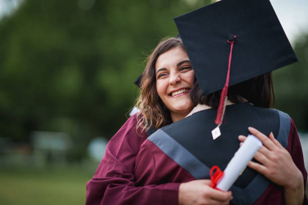 istock Group of college students  embracing on graduation day. 2156211181