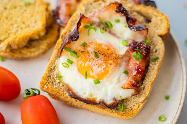 istock Baked Bacon and Eggs in Bread on White Plate with Fresh Green Onion Close-Up 2156211739