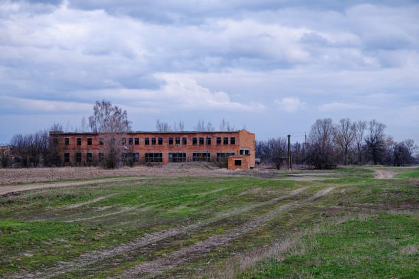 istock An abandoned brick building, surrounded by wild grass, under a gloomy sky. 2156212057