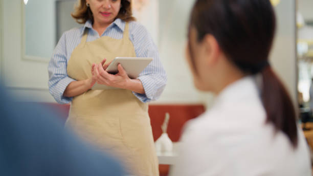 istock Waitress taking orders from three diverse business people in cafe restaurant during lunch break time 2156214823