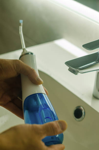 istock Men hands hold the oral electronic irrigator in the bathroom 2156216254