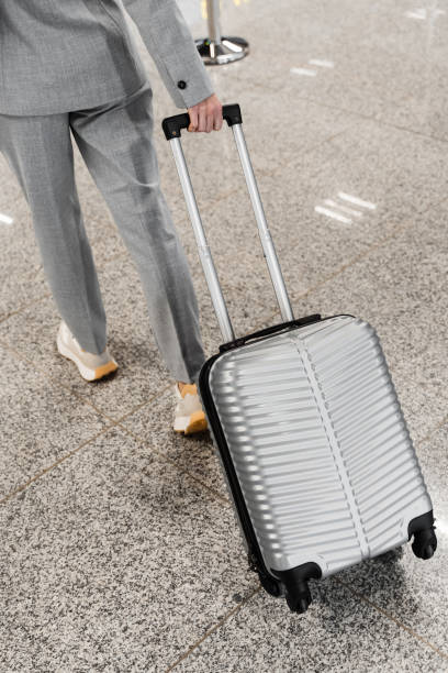 istock A passenger holds a handgrip and pulls a suitcase in the airport lobby. Close up image of luggage at the airport. 2156216454