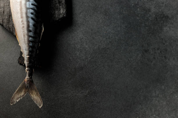 A visually stunning display of smoked mackerel herring on a sleek black cutting board against a dark background. Perfect for food enthusiasts and menu designs, this image captures the allure of gourmet seafood