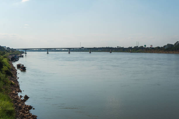 A river with a bridge in the background. The water is calm and the sky is clear. The bridge is a large structure that spans across the river