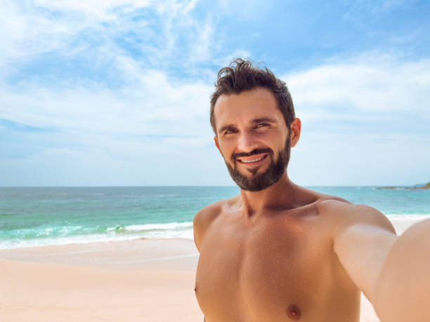 istock Smiling Man Taking Selfie on Sunny Beach Day 2156221472