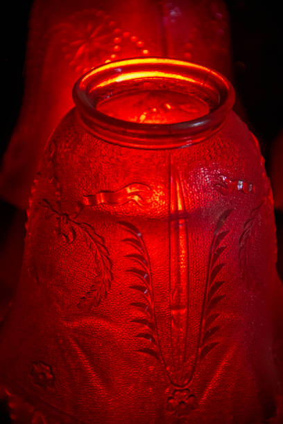 An antique etched-glass lampshade for a small lamp that may have graced a bedside table during the first half of the twentieth century.\n\nHere, it appears red because of backlighting from a red lamp.