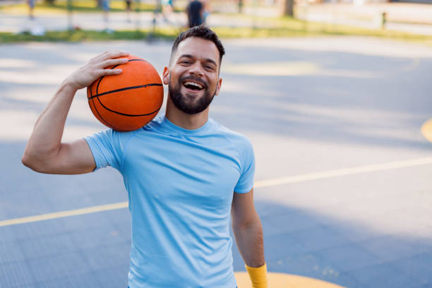 istock Man holding basketball standing on court 2156233005