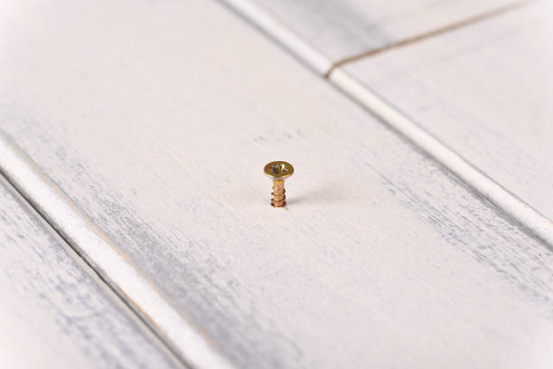 Twisting the screw into a wooden board using cordless screwdriver.