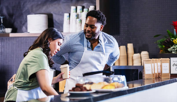 istock Two multiracial workers behind counter in coffee shop 2156234350