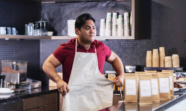 istock Young Asian man working behind counter in coffee shop 2156234358