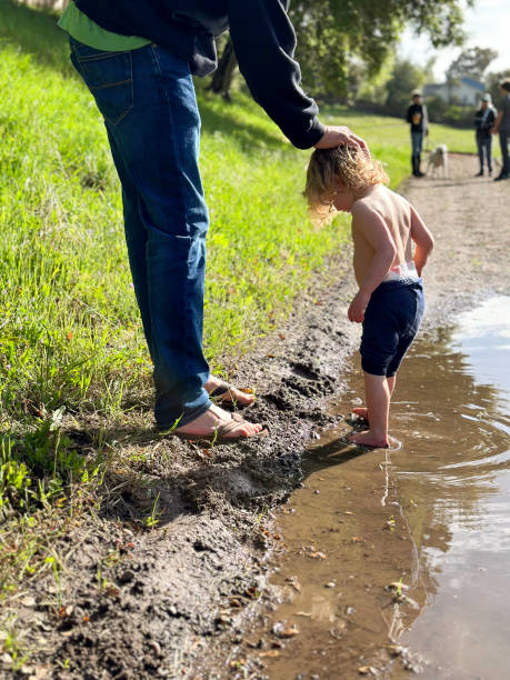 istock Father and toddler play outside in a puddle 2156235271