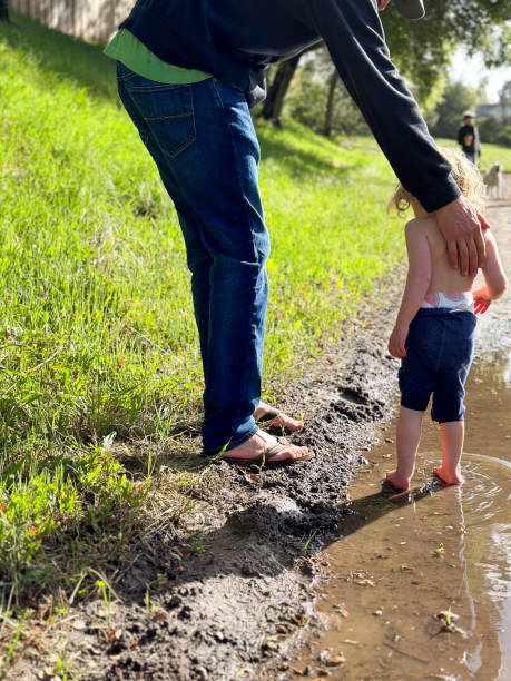 istock Father and toddler play outside in a puddle 2156235361