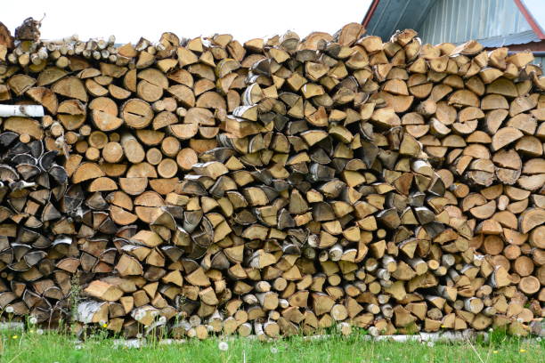 istock a stack of wood with a house in the background 2156236040