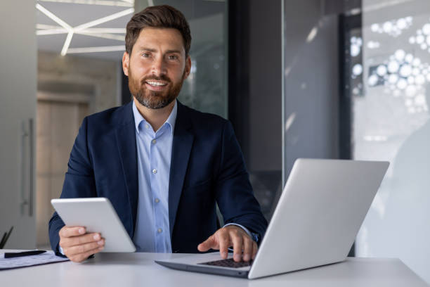 istock Confident businessman working with laptop and tablet in office 2156237757