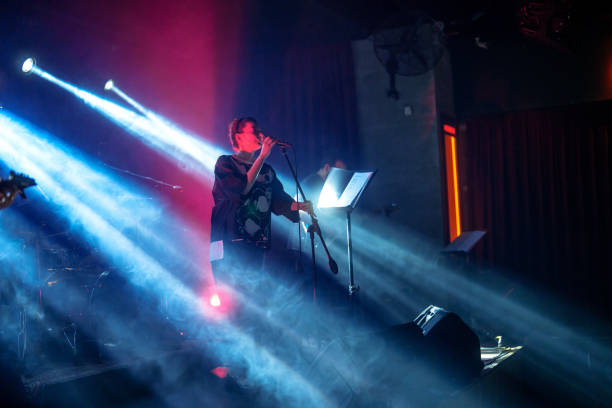 istock Vocal singer performing on stage with colorful stage lights. 2156238515