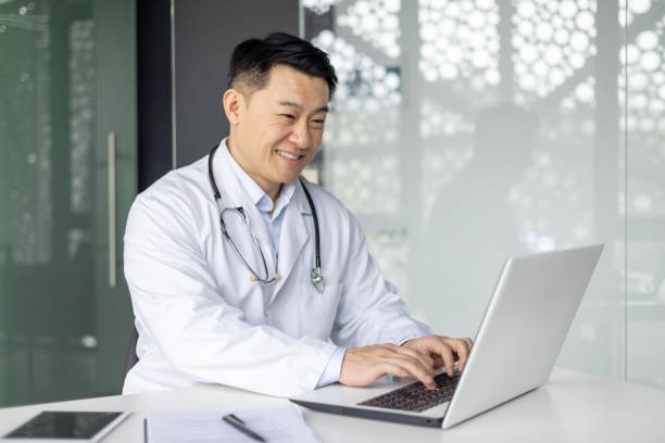 istock Asian mature doctor working on laptop in office with a cheerful expression 2156238871