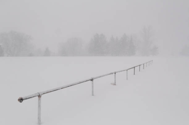 A rail sits freezing in an empty farmers field while a winter storm covers the world in a fresh layer of snow.