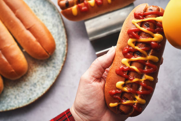 istock Preparing Hot Dog with Roasted Onions, Pickle Relish, Mustard and Ketchup 2156240708
