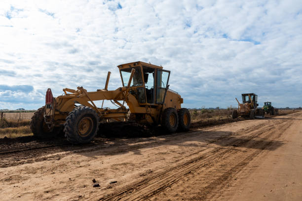 istock Heavy Machinery Working on Rural Dirt Road Under Partly Cloudy Sky 2156241430