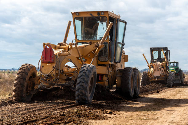 istock Heavy Machinery Working on Rural Dirt Road Under Partly Cloudy Sky 2156241436