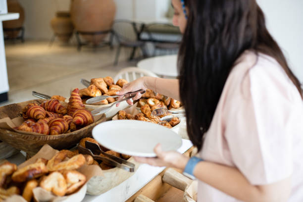 Woman taking delicious croissant from buffet