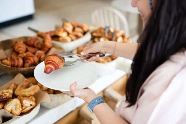Woman taking delicious croissant from buffet