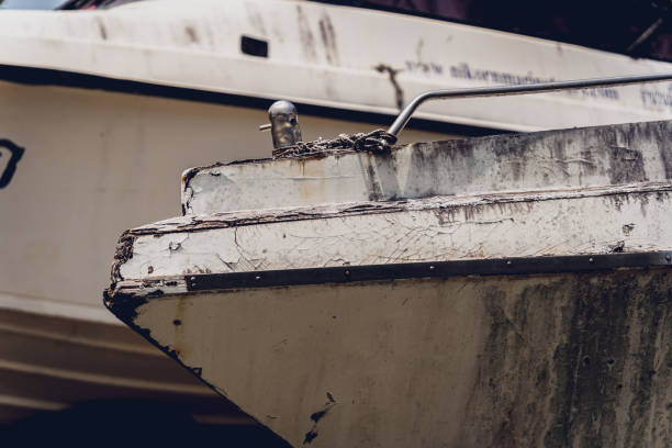 Old and rusty motor boats on a landfill surrounded by tropical forest.
