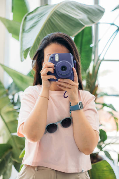 istock Woman taking photos with instant camera 2156247394