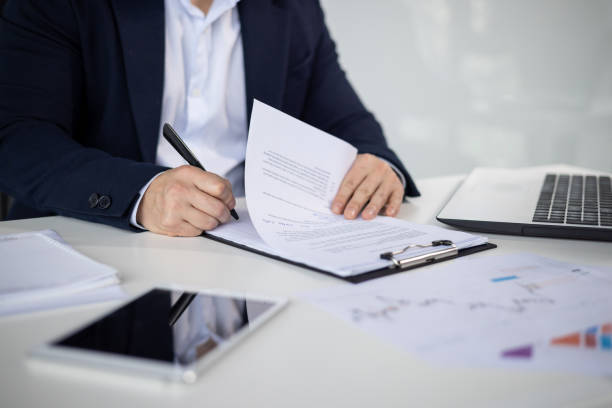 istock Businessman signing documents at office desk with laptop and tablet 2156248977
