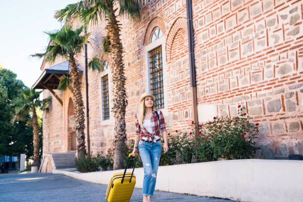 istock Tourist walking by historic building with palms 2156250840