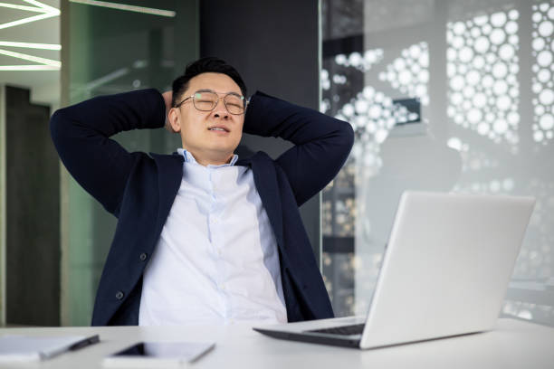 istock Asian mature man relaxing at desk with laptop in modern office setting 2156251227