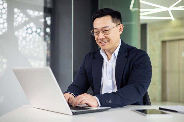 istock Asian mature man working on a laptop in modern office environment 2156251533