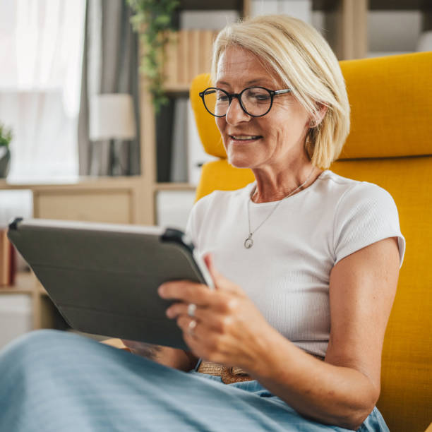 istock Mature senior woman sit at home and use tablet 2156252636