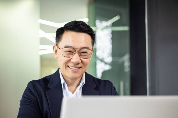 istock Smiling Asian businessman working on laptop in modern office 2156255069