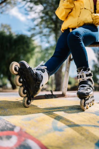 A woman is sitting on a bench with her roller skates on. The scene is set in a park with a yellow background