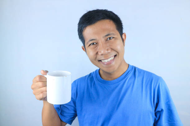 istock Smiling expression young asian man wearing t-shirt holding coffee cup, isolated on white background 2156258288