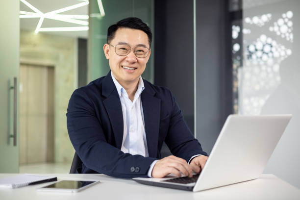 istock Confident businessman smiling while working on laptop in modern office 2156258683