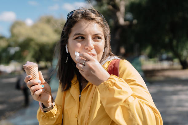 istock A woman in a yellow jacket is eating an ice cream cone 2156259467