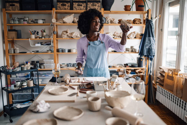 istock Happy diverse potter smiling at clay work and standing at pottery studio 2156262105
