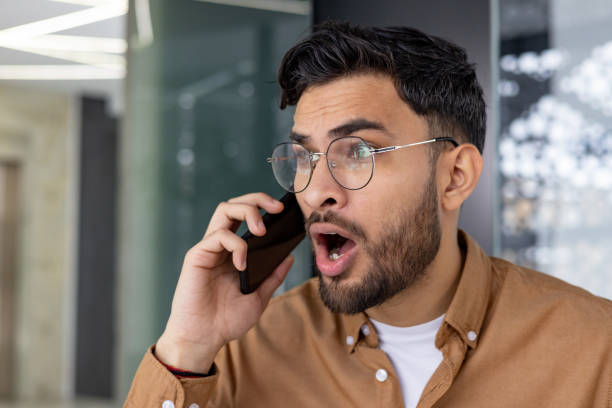 istock Man expressing shock and surprise while talking on phone indoors 2156264741