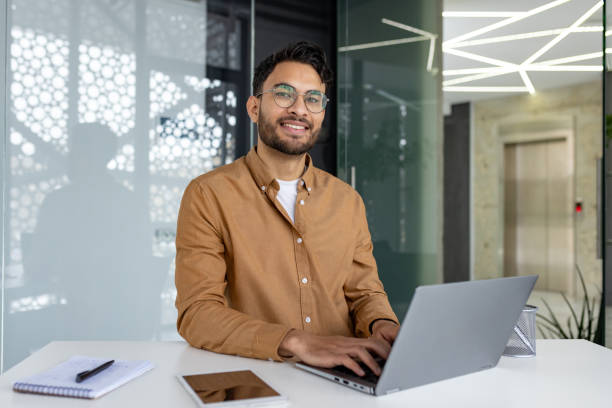 istock Smiling businessman working on laptop in modern office setting 2156265284