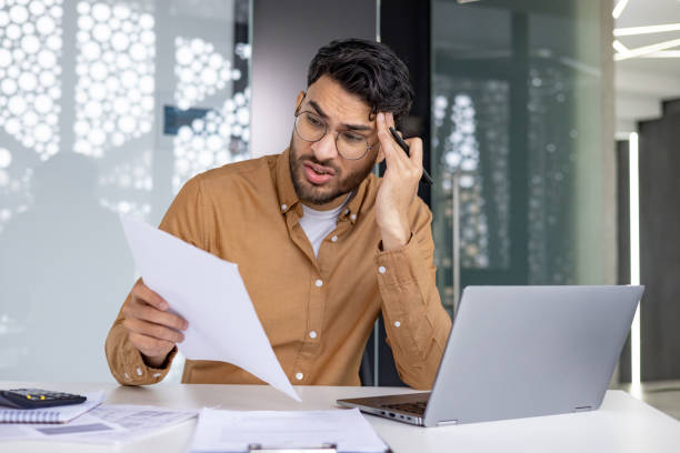 istock Stressed businessman analyzing documents at his desk in modern office 2156265338