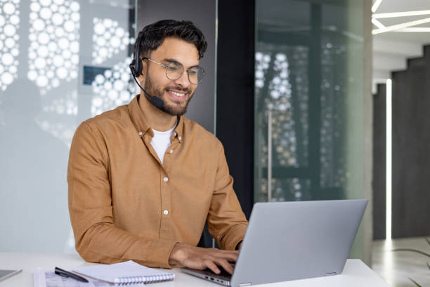 istock Smiling customer service representative working at laptop with headset in modern office 2156265800
