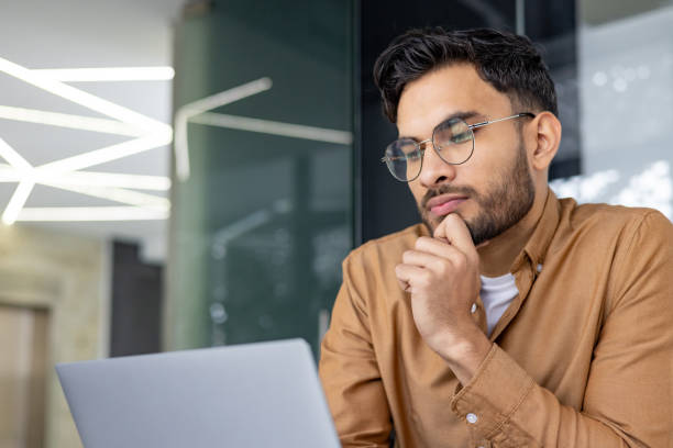 istock Pensive man working on laptop in modern office environment 2156268109