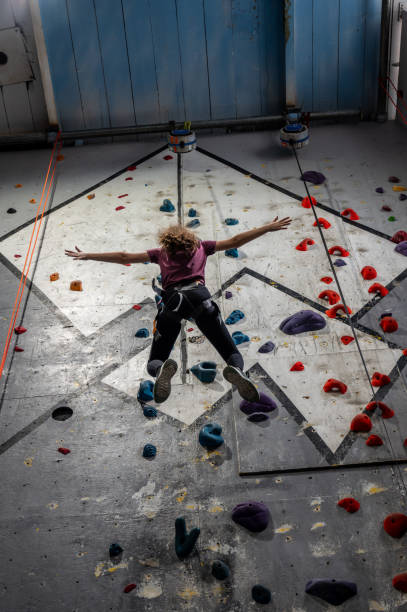 Teenage girl going down from indoor climbing wall seen from below.